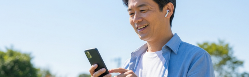 散歩をしながらオーディブルを楽しむ男性。場所を選ばないので喜んでいるイメージ