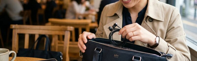 お洒落なビジネスバッグのサイドポケットから、絡まっていない綺麗な有線イヤホンをスッと取り出す瞬間のクローズアップ
