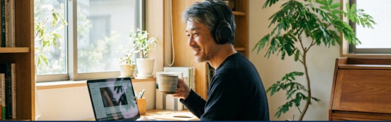 お気に入りのワイヤレスイヤホンを耳につけ、穏やかな笑顔でパソコン作業している
