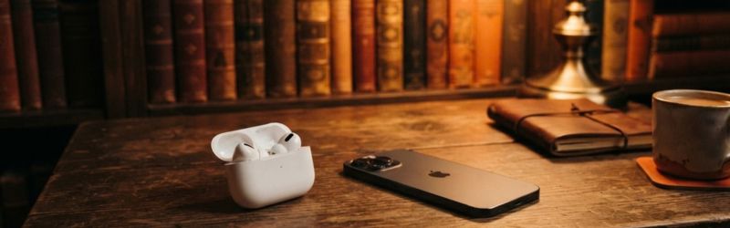 古い書斎のデスクに白いワイヤレスイヤホンとスマホが置かれている